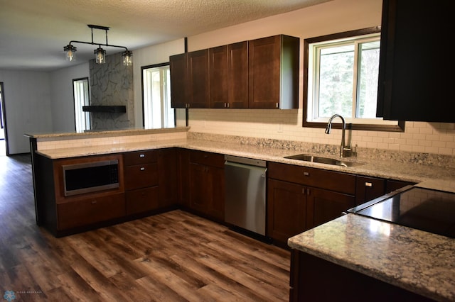 kitchen featuring dark wood-type flooring, sink, appliances with stainless steel finishes, kitchen peninsula, and pendant lighting