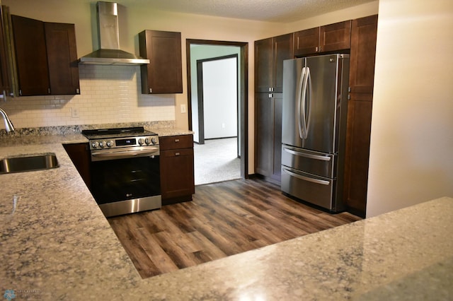 kitchen with wall chimney exhaust hood, sink, appliances with stainless steel finishes, dark hardwood / wood-style flooring, and backsplash