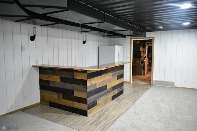 bar featuring hardwood / wood-style flooring and fridge