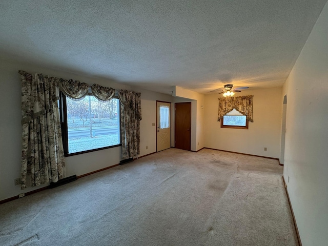 carpeted empty room with ceiling fan and a textured ceiling