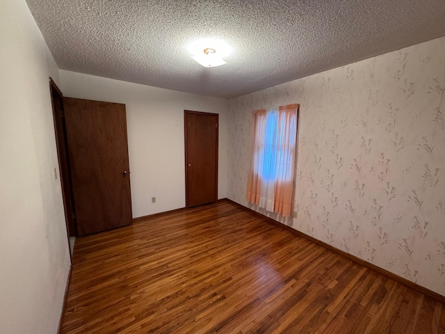 unfurnished room featuring wood-type flooring and a textured ceiling