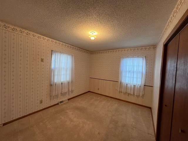 carpeted empty room featuring a textured ceiling