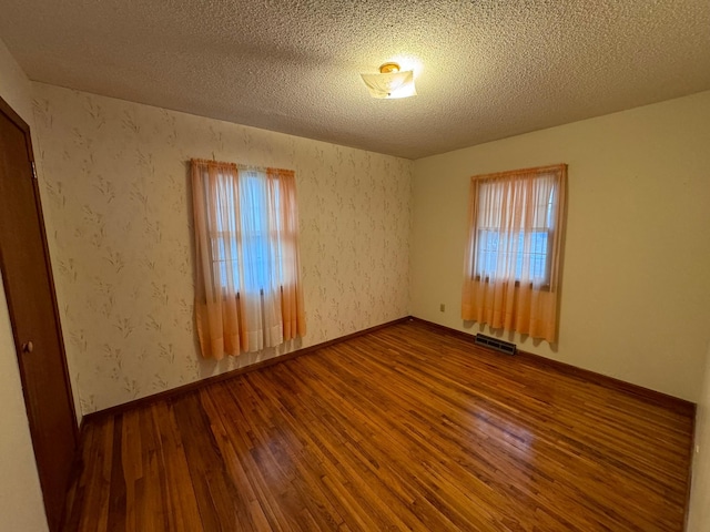 unfurnished room featuring hardwood / wood-style flooring and a textured ceiling