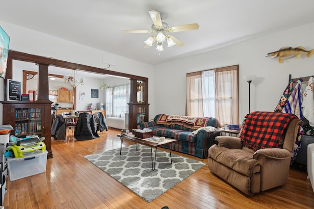 living room featuring ceiling fan with notable chandelier and light wood-type flooring