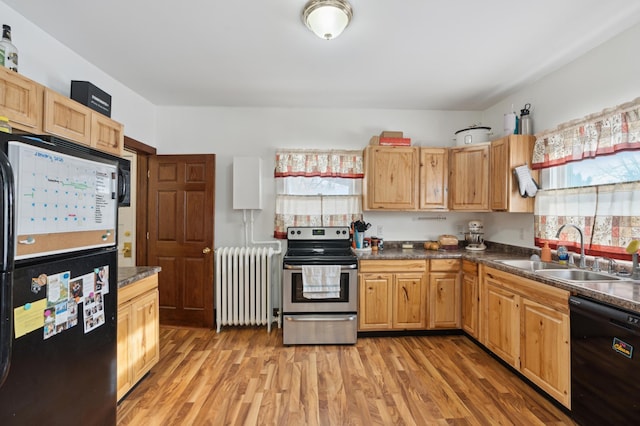 kitchen featuring radiator, sink, light wood-type flooring, and black appliances