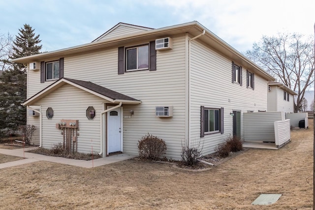 front of property featuring an AC wall unit and a front lawn