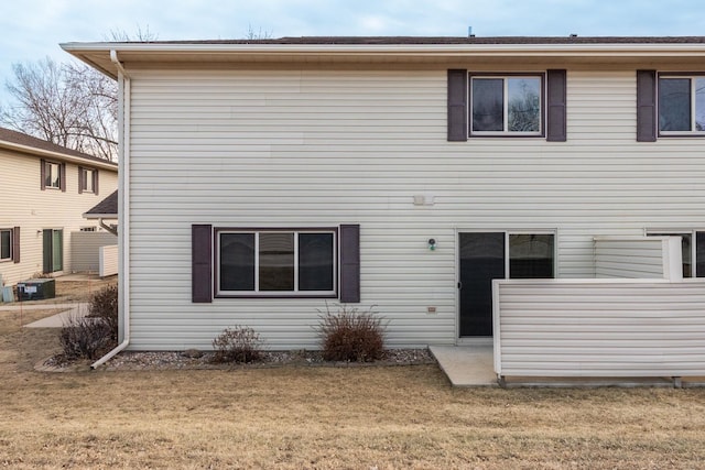 rear view of property with cooling unit and a yard