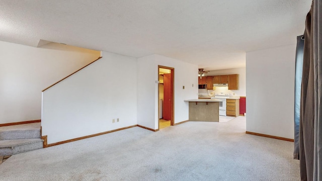 unfurnished living room featuring light colored carpet and ceiling fan