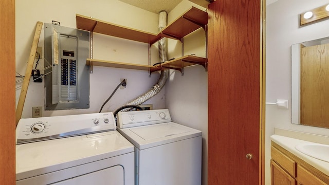 washroom featuring washing machine and clothes dryer, electric panel, and sink