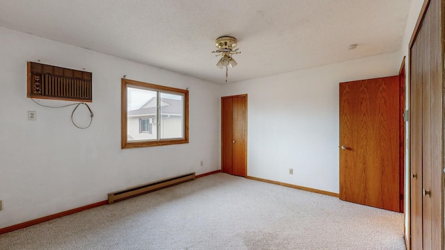 carpeted spare room featuring ceiling fan, a wall mounted air conditioner, a textured ceiling, and baseboard heating