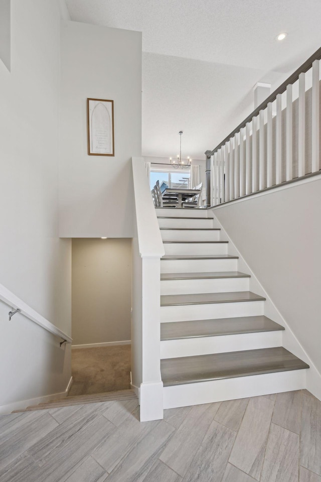 stairway featuring a notable chandelier