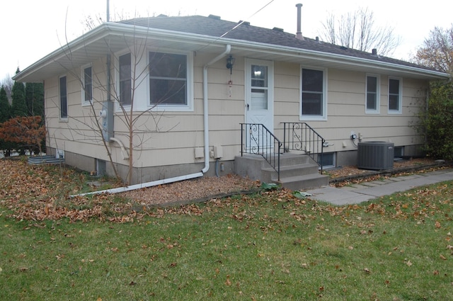 view of front of home with a front yard and central air condition unit