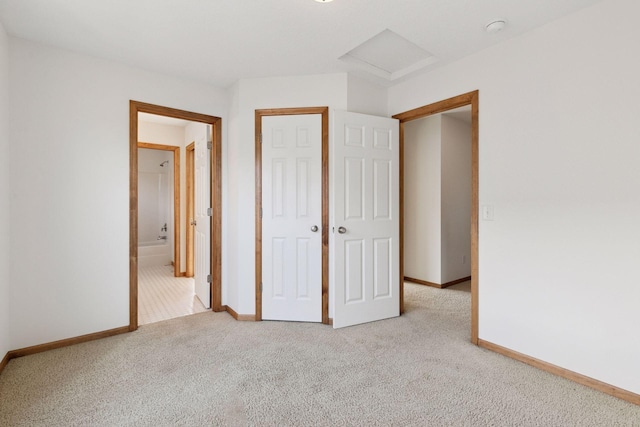 unfurnished bedroom featuring attic access, carpet, a closet, and baseboards