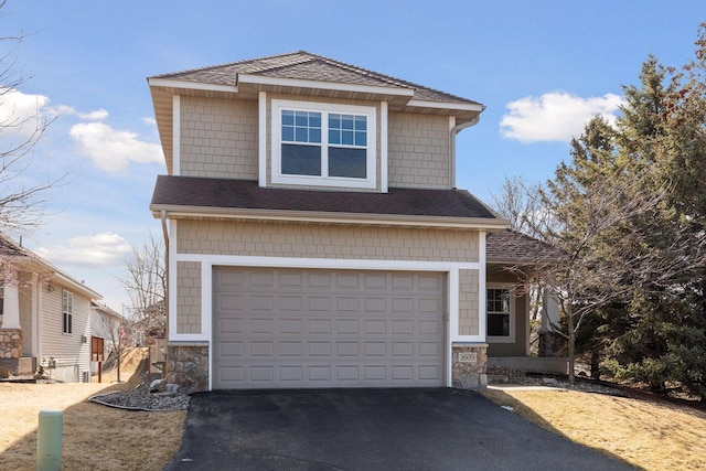 view of front of property featuring driveway, stone siding, an attached garage, and a shingled roof