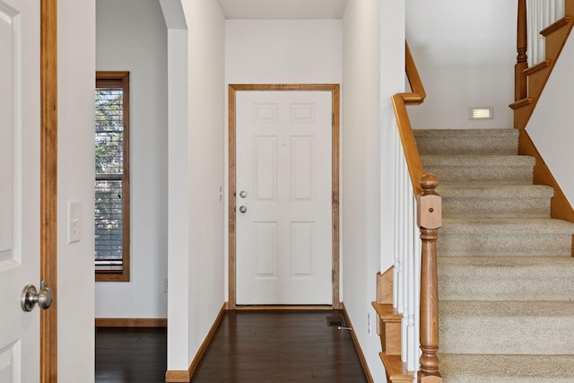 entryway featuring arched walkways, dark wood finished floors, visible vents, baseboards, and stairs