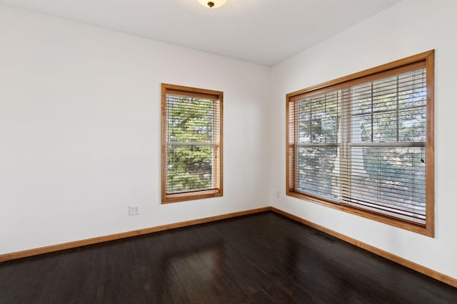 empty room with visible vents, baseboards, and dark wood-style flooring