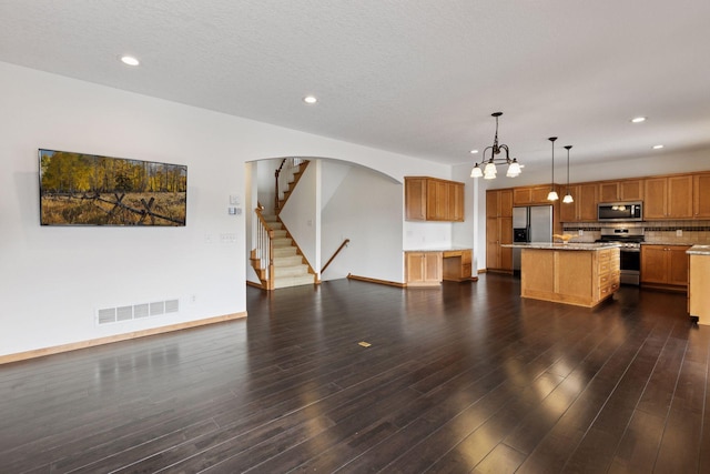 kitchen with dark wood-style flooring, visible vents, open floor plan, appliances with stainless steel finishes, and a center island