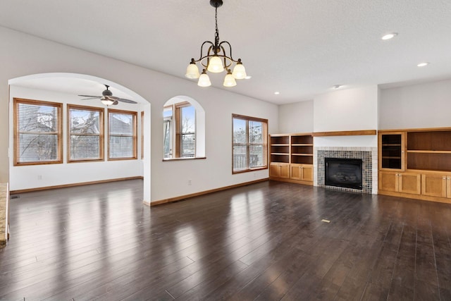 unfurnished living room featuring dark wood-style floors, recessed lighting, a textured ceiling, a tile fireplace, and baseboards