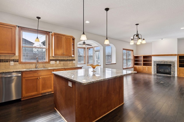 kitchen featuring dark wood-style floors, tasteful backsplash, a kitchen island, a sink, and dishwasher