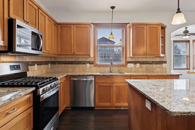 kitchen featuring a sink, appliances with stainless steel finishes, decorative backsplash, brown cabinets, and dark wood-style floors