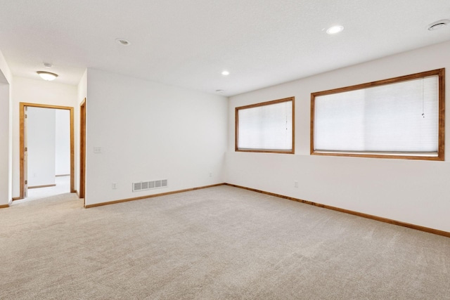 spare room featuring light colored carpet, visible vents, baseboards, and recessed lighting