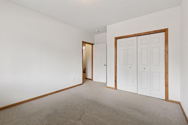 unfurnished bedroom with carpet, a closet, a textured ceiling, and baseboards