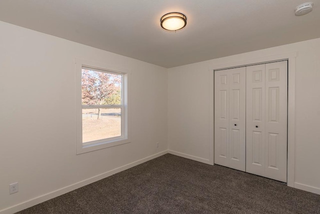 unfurnished bedroom with dark carpet and a closet