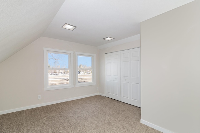 bonus room with vaulted ceiling and light colored carpet