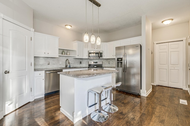 kitchen with sink, white cabinetry, a center island, hanging light fixtures, and appliances with stainless steel finishes