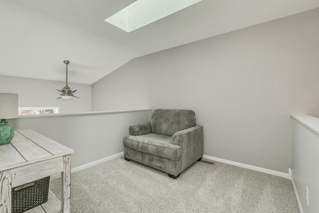 living area with lofted ceiling with skylight, ceiling fan, and carpet flooring