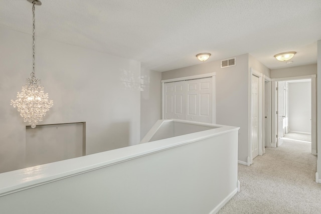 hallway with light carpet and a textured ceiling