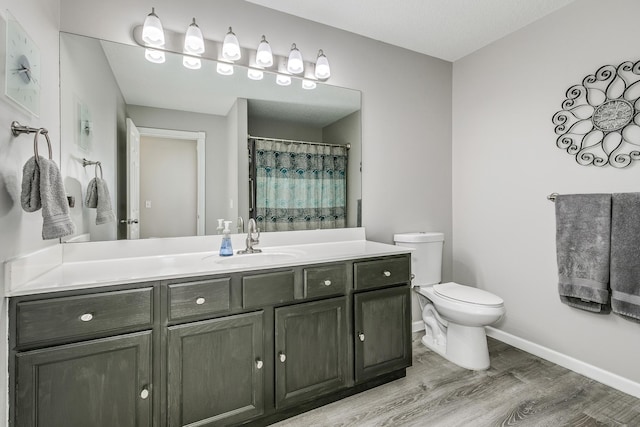 bathroom with wood-type flooring, toilet, curtained shower, and vanity