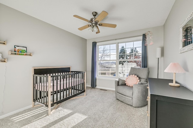 bedroom featuring a crib, carpet floors, and ceiling fan