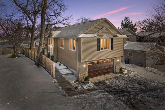 view of front of house with driveway, an attached garage, and fence