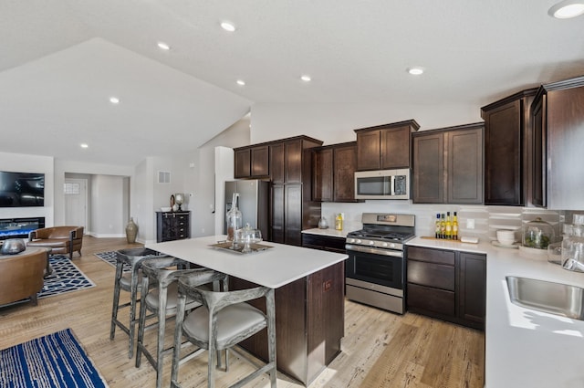 kitchen featuring a kitchen island, backsplash, a kitchen breakfast bar, stainless steel appliances, and light wood-type flooring