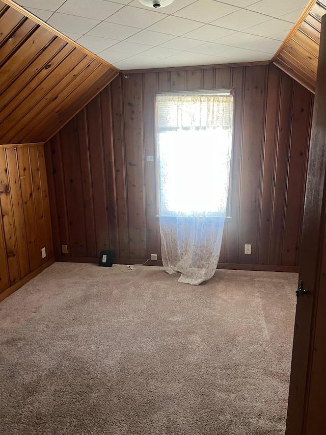 additional living space featuring lofted ceiling, carpet flooring, and wood walls