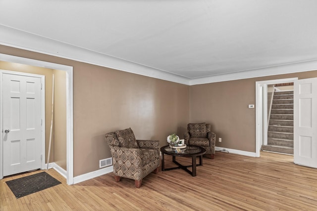 living area featuring ornamental molding and light wood-type flooring