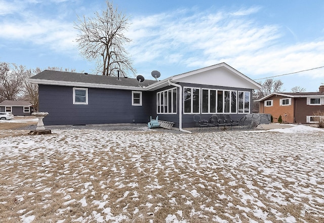 snow covered property with a patio area and a sunroom