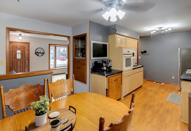 kitchen with stainless steel fridge, oven, ceiling fan, light brown cabinets, and light wood-type flooring