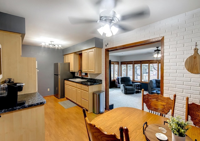 kitchen with light brown cabinetry, sink, stainless steel fridge, ceiling fan, and light hardwood / wood-style floors