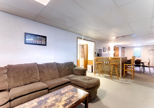 living room featuring a drop ceiling, carpet floors, and bar area