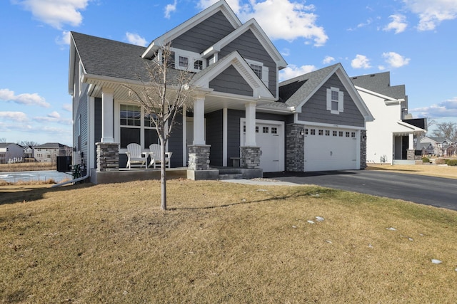 craftsman inspired home featuring stone siding, aphalt driveway, roof with shingles, a porch, and a front yard