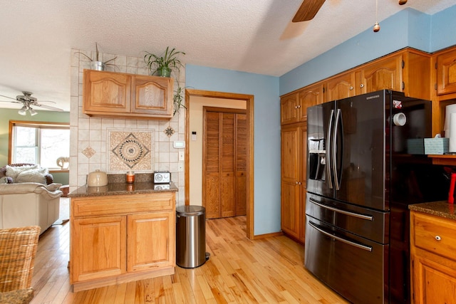 kitchen with black fridge, ceiling fan, light hardwood / wood-style flooring, and a textured ceiling