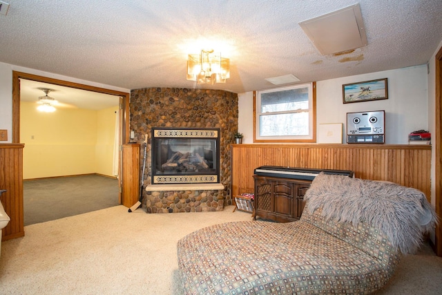 living area featuring a stone fireplace, carpet, and a textured ceiling