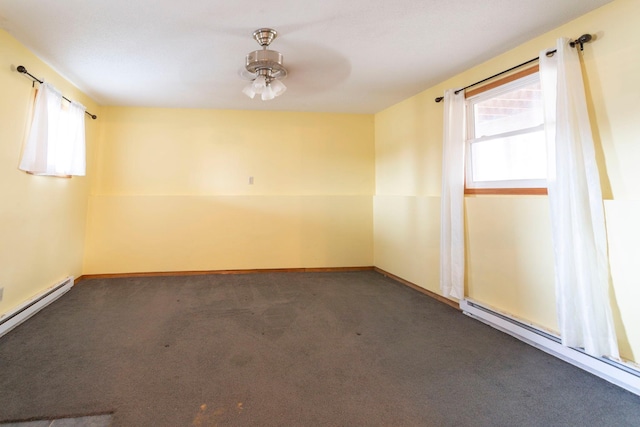 spare room featuring a baseboard radiator, dark carpet, and a wealth of natural light