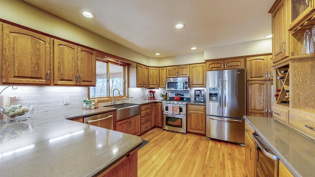 kitchen featuring tasteful backsplash, sink, stainless steel appliances, and light hardwood / wood-style floors