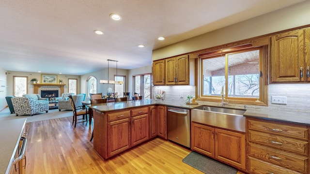 kitchen featuring sink, dishwasher, kitchen peninsula, pendant lighting, and light hardwood / wood-style floors