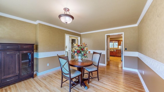 dining room with ornamental molding and light hardwood / wood-style floors