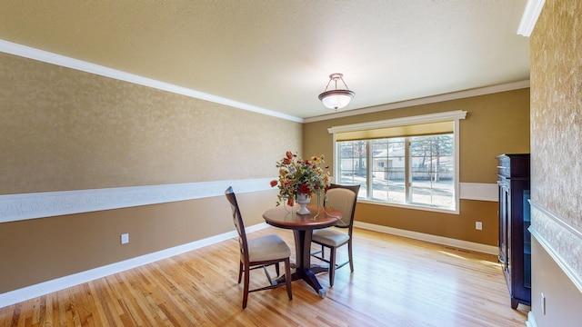 dining room with ornamental molding, a fireplace, and light hardwood / wood-style flooring