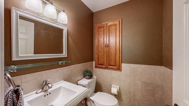 bathroom with tile walls, sink, and toilet